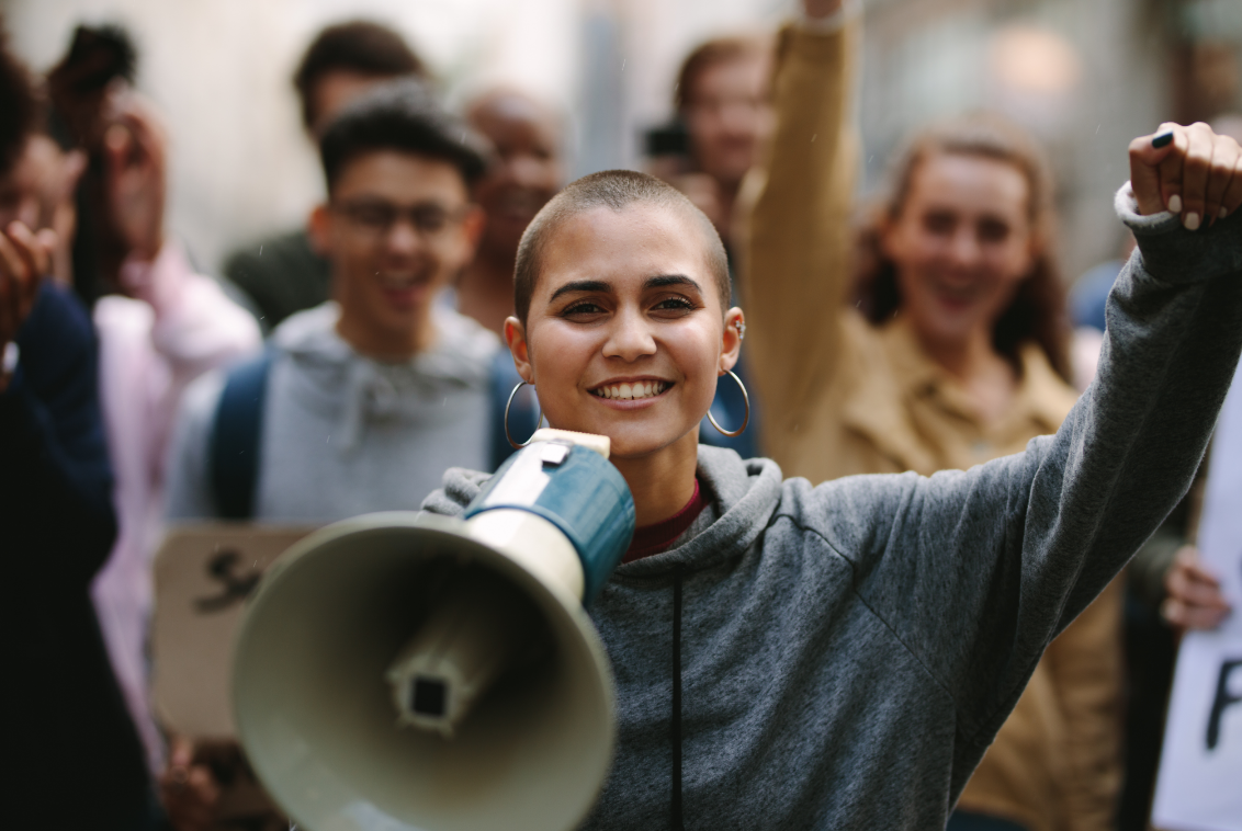 woman smiling leads crowd with megaphone